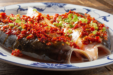 A view of a plate of steamed fish head topped with red pepper paste.
