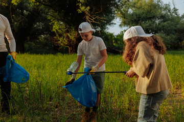 Volunteers collecting plastic waste in a meadow using trash picker and bags