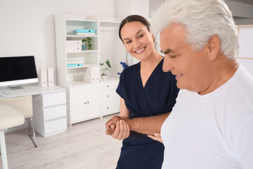 Fototapeta premium Female therapist with senior man walking in rehabilitation center