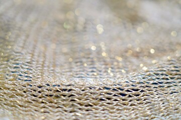 Close-up of shimmering golden yarn in openwork crochet with shallow depth of field