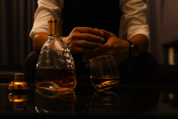 A highly experienced businessman in a tuxedo quietly pours whiskey in his home. A wealthy gentleman who exudes elegance, power and the contemplative luxury of nightlife.
