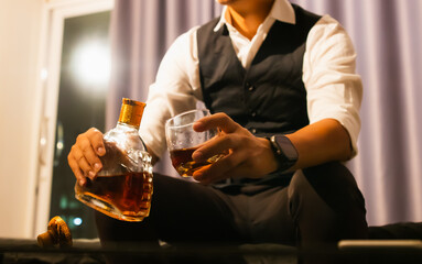 A highly experienced businessman in a tuxedo quietly pours whiskey in his home. A wealthy gentleman who exudes elegance, power and the contemplative luxury of nightlife.