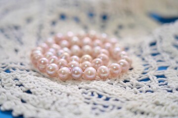 Pink pearl necklace on delicate crochet lace background