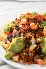A closeup view of a plate of vegan chorizo loaded fries.