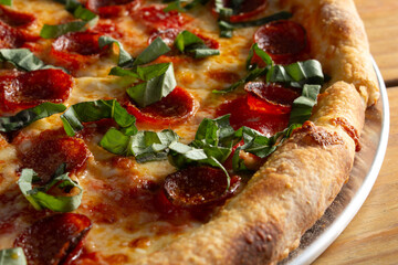 A closeup view of a pepperoni and basil pizza.