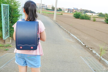 小学生の後ろ姿を写した写真。ランドセルを背負い歩く姿が、入学や通学のイメージ、子供の成長を象徴する日本の学校生活素材
