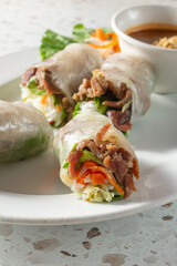 A view of a plate of griled pork spring rolls.