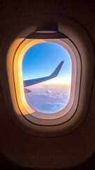 Airplane window view of sunrise over clouds