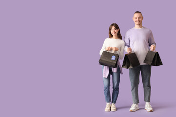 Young couple with shopping bags on lilac background. Cyber Monday