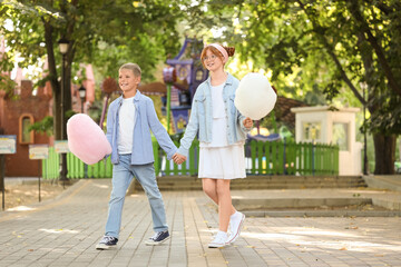Teen girl and boy with cotton candy holding hands in park
