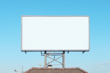 Obraz premium Front view of a blank billboard on the roof of a building against a clear blue sky. Mockup.