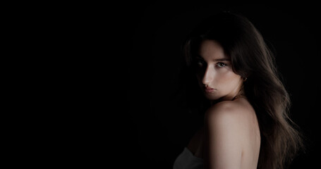 Fashion model with long brown hair posing in studio, creating a captivating portrait with a...