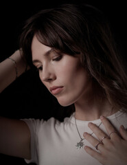 Studio portrait of a young woman with hand on hair and touching her necklace