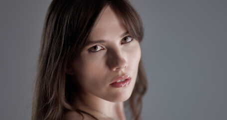 Fototapeta premium Studio portrait of beautiful fashion model with long brown hair posing over gray background