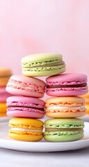 Obraz premium Stack of colorful macarons on a white plate; pink backdrop