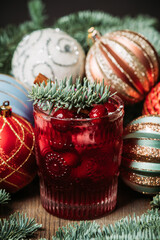 Cocktail based on gin with cranberry juice and decorated with fir branches and christmas balls on...