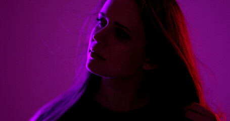 Fashion model posing with purple and red ambient lights during a studio photoshoot