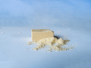 Close-up of a stock cube with scattered powder on a blue and white background, representing cooking seasoning, instant broth, food flavoring, and essential culinary ingredients in the kitchen.