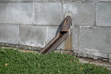 A fragment of a rusty downpipe on the wall of a house on an autumn day