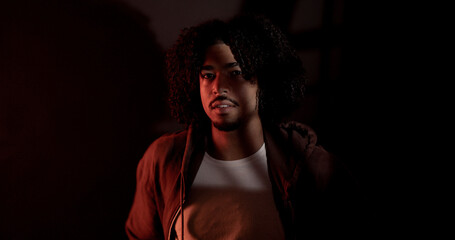 Obraz premium Confident male model with curly hair posing under red light in a professional studio photoshooting