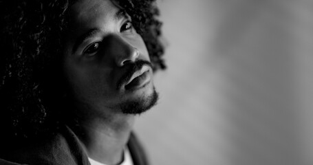 Black and white portrait of a young man with afro hair looking up, expressing contemplation and introspection