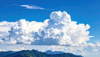 Vivid sky filled with massive, fluffy white clouds over dark green mountains