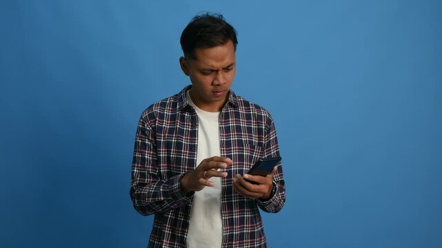 Worried young Asian boy looking at a phone and does not understand why it is not working. The angry student does not believe the bad news he saw.