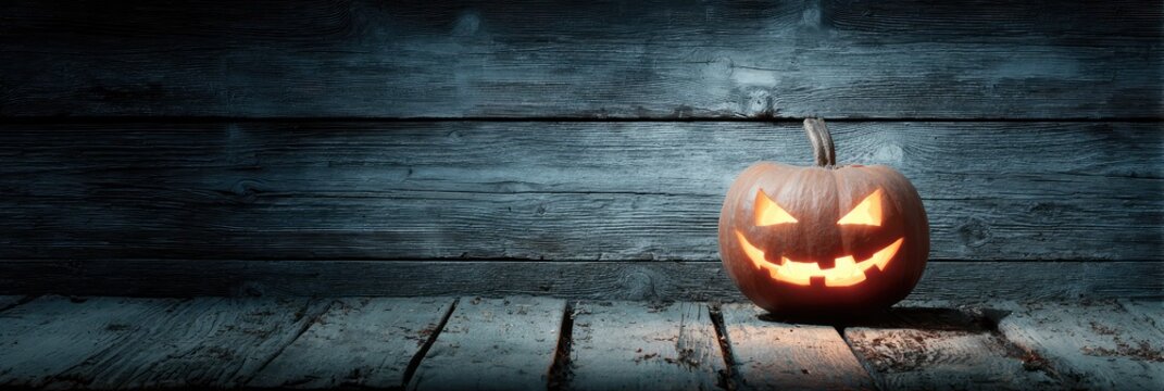 ominous. Carved Halloween pumpkin emitting an eerie orange glow, placed on weathered wooden planks for a spooky effect. event programs.