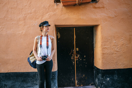 Photographer holding camera exploring city street during summer vacation