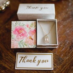 A delicate gold necklace with baguette-cut diamonds rests in a gift box, accompanied by thank-you notes with floral patterns.