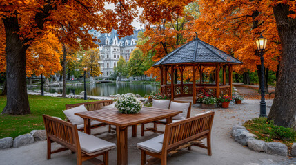 Obraz premium Outdoor dining area with wooden table and chairs surrounded by vibrant autumn foliage, featuring a gazebo and serene lake view, creating a peaceful retreat atmosphere