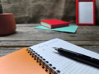Close-up of a pen lying on a notebook with the inscription daily task