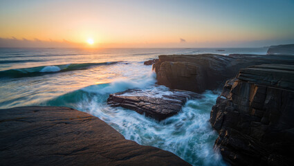 Obraz premium Sunrise over rugged coastal rocks with crashing waves