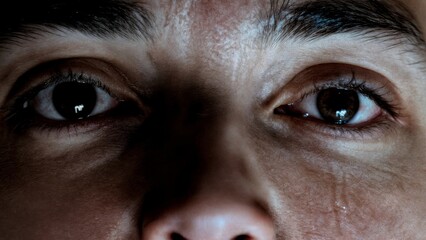 A person's face partially obscured by shadow, with a single tear. Regret, guilt, criminal, consequences, legal.