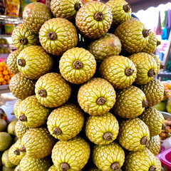 Fototapeta premium Stack of Salak fruits with scaly skin texture displayed in natural light at a market stall.