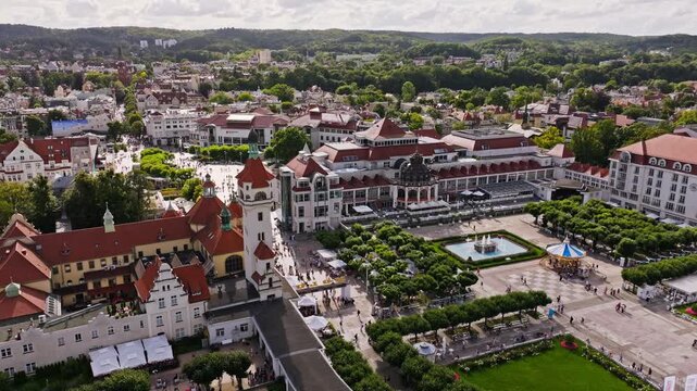 Scenic aerial shot shows Sopot city center with tourists and green hills beyond