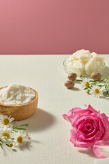 Minimal top view with shea butter, roses and chamomile scattered gently across background. Organic beauty and skincare concept with open area for text.