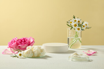 Arrangement of shea butter and roses with chamomile flowers in a glass vase, styled on beige surface. Elegant photo of natural skincare ingredients with copy space.