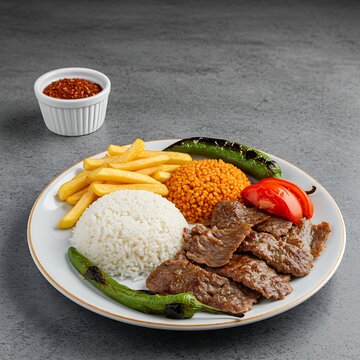 Delicious Turkish Iskender Kebab Plate with Rice, Bulgur, Fries, and Grilled Vegetables