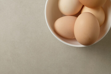 Perfectly arranged brown eggs in a white bowl on a simple surface