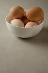 Fresh eggs in a white bowl on a neutral background showcasing simple beauty