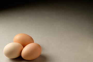 Fresh eggs standing together on a smooth gray surface