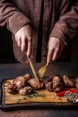 Hands cutting grilled beef steak on wooden board