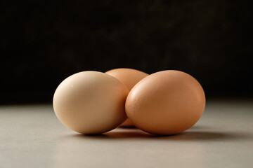 Three farm-fresh eggs resting elegantly on a smooth surface in soft light