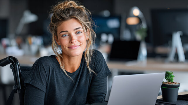 Confident young woman in a wheelchair working on laptop at modern office, inclusive workplace concept