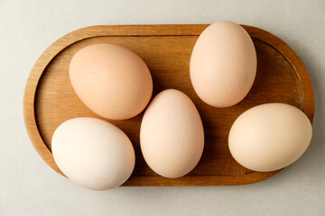 Fresh brown eggs arranged on a wooden platter in a cozy kitchen setting