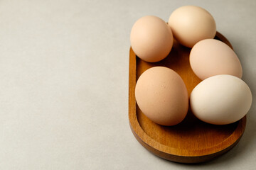 Five beautiful eggs arranged on a wooden plate in a cozy kitchen setting