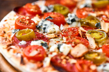 Pizza with salami, jalapeno pepper, cherry tomatoes and mozzarella cheese. Soft focus.	