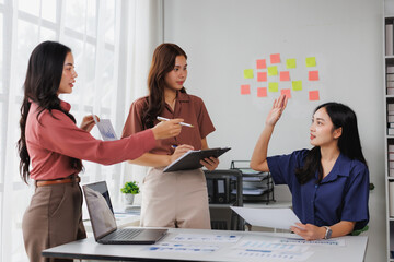 Businesswomen discussing charts and brainstorming with sticky notes