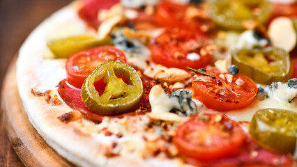 Pizza with salami, jalapeno pepper, cherry tomatoes and mozzarella cheese. Soft focus.	